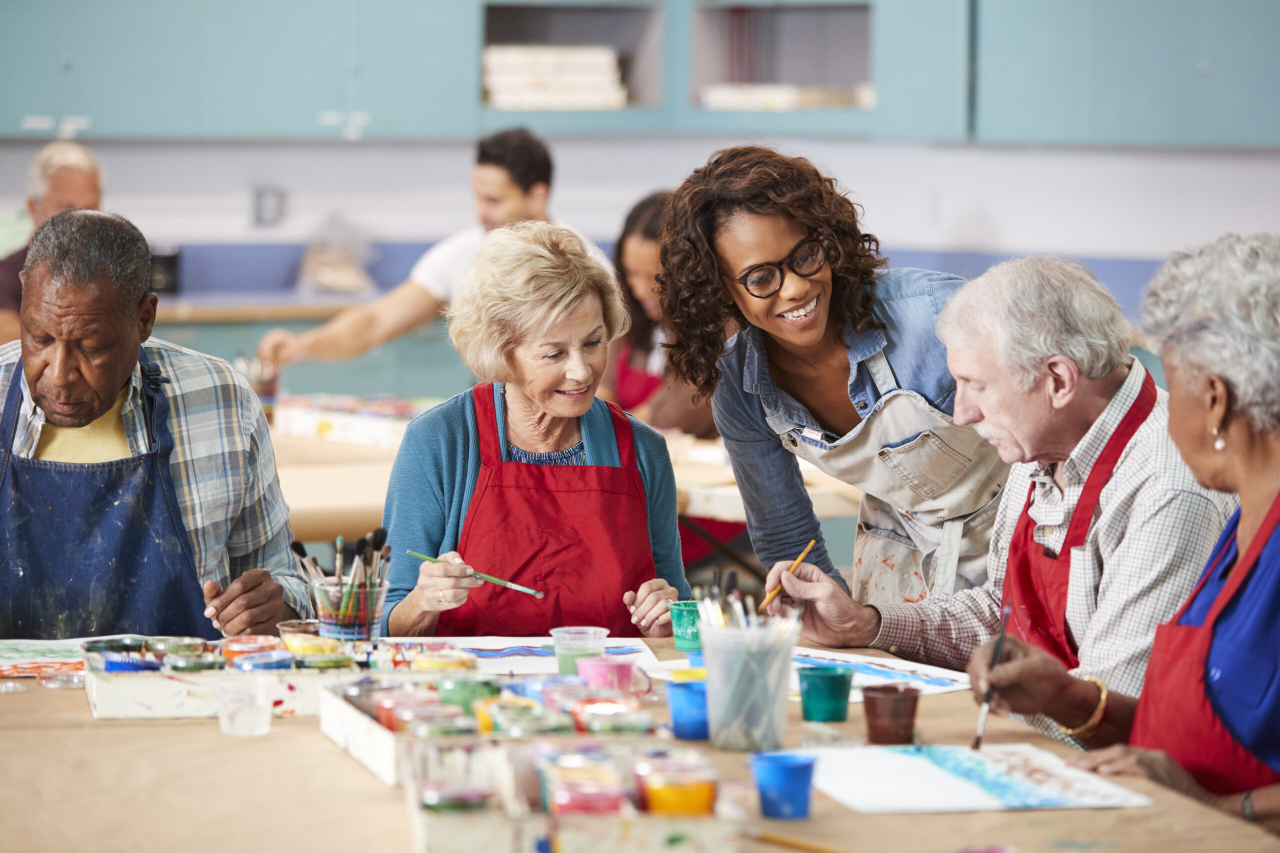 Group Of Retired Seniors Attending Art Class In Community Centre With Teacher Group Of Retired Seniors Attending Art Class In Community Centre With Teacher